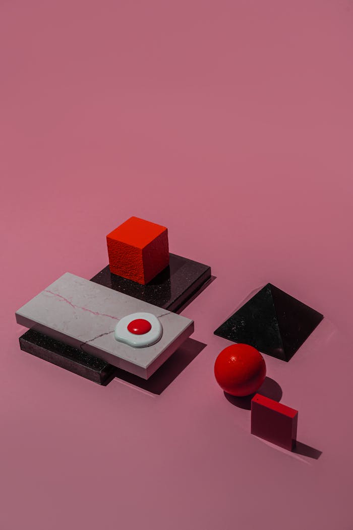Conceptual composition of colorful geometric shapes on a pink background, highlighting contrasts.